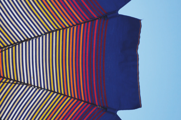 Striped beach parasol against blue sky