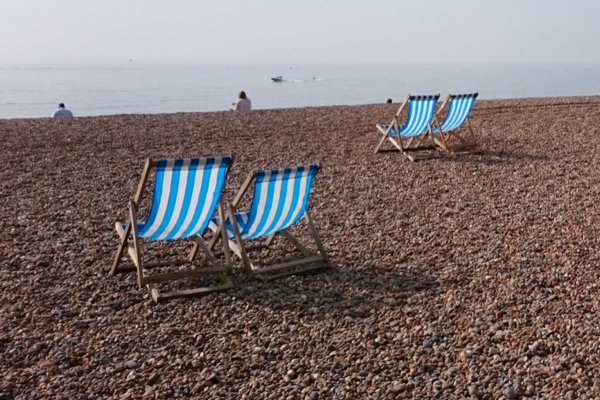 Brighton beach with four blue and white striped deckchairs